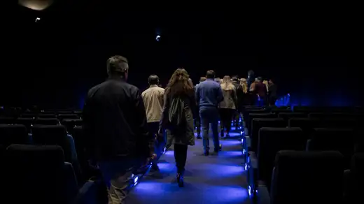 Spettatori con giacche e borse in un corridoio di cinema