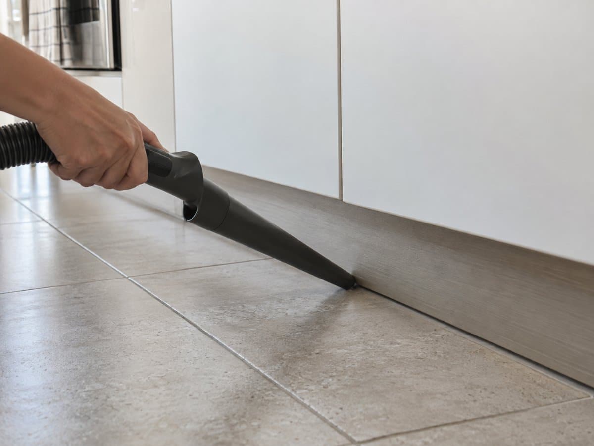 Aspirapolvere che pulisce lo zoccolo di un mobile da cucina