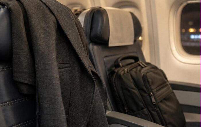 Giacca e zaino da cabina appoggiati sui sedili di un aereo di linea