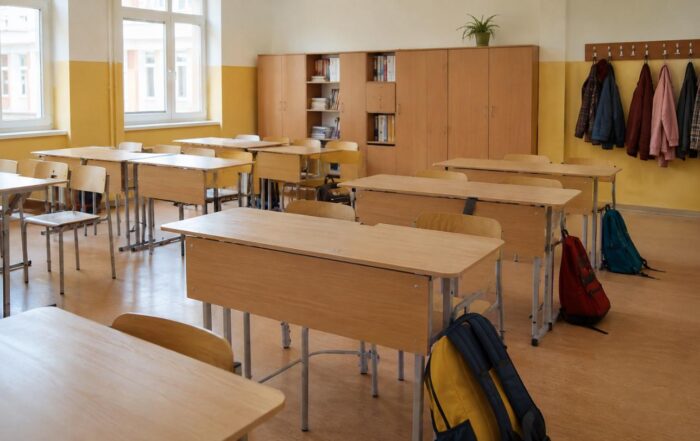 Zaini scolastici appoggiati sul pavimento di un’aula e giacche appese: le vie di passaggio delle cimici dei letti a scuola