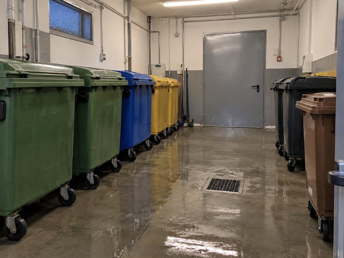 Locale rifiuti di un negozio con contenitori chiusi e pavimento lavato