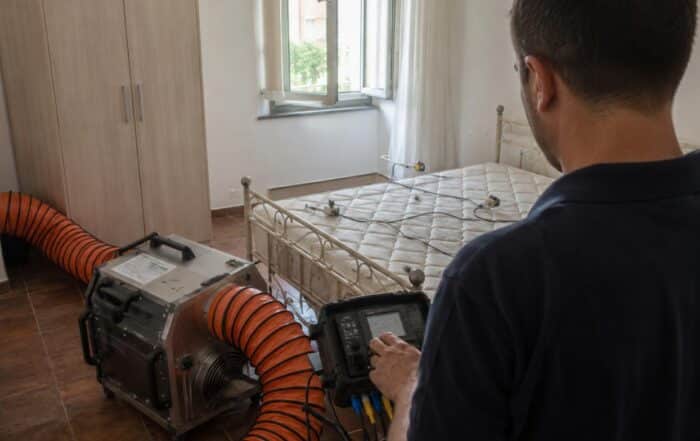 Tecnico Ekonore controlla la centralina delle sonde termiche durante il trattamento a calore controllato fino a 60 gradi in una camera di struttura ricettiva contro le cimici dei letti