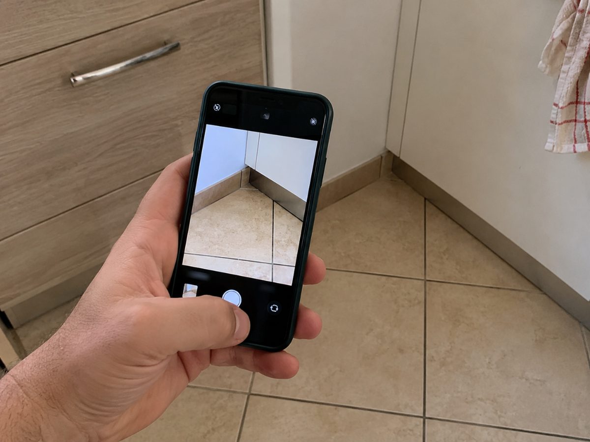 Smartphone che fotografa un angolo del pavimento di una cucina